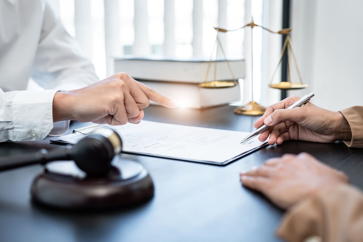 deux personnes assises autour d'une table avec un document et un marteau du juge placés sur la table 