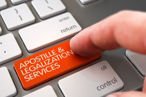 doigt appuyant sur une touche orange d'un clavier qui mentionne "apostille & legalization services"