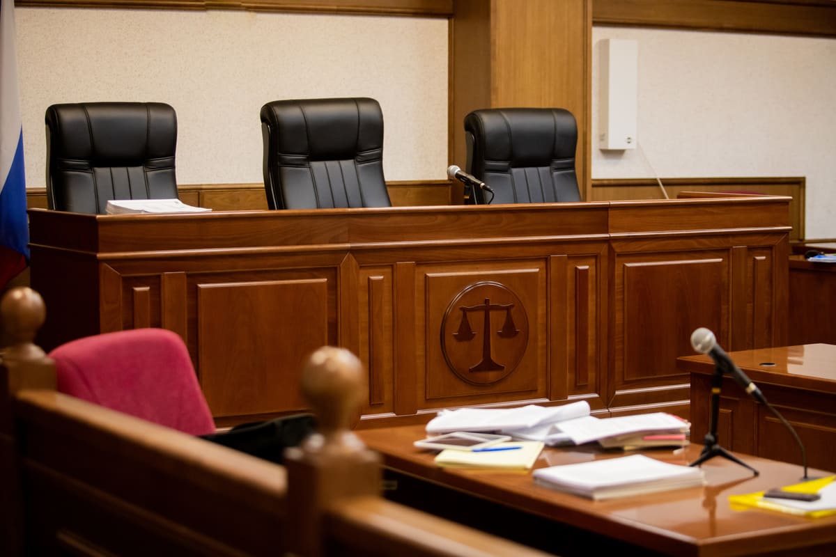 salle d'audience du tribunal vide avec plusieurs document posés sur la table près du micro  