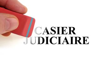 main tenant une gomme pour effacer l'inscription casier judiciaire sur une feuille blanche