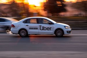 voiture blanche roulant avec un logo Uber en noir inscrit sur le côté